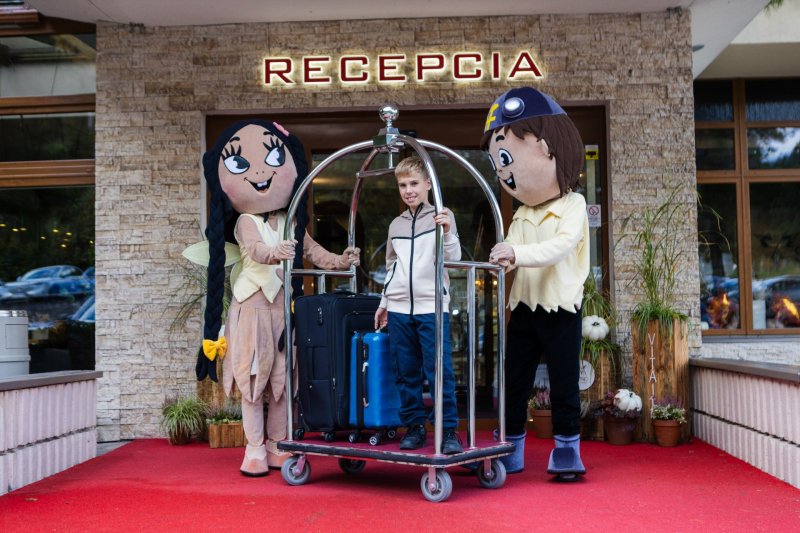 Maskoti Kopko a Svetluška s dieťaťom pred hotelom